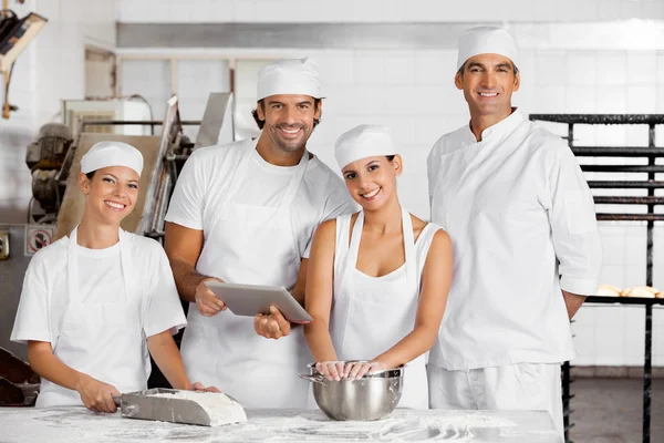 Panaderos confiados usando tableta digital juntos en la mesa —  Fotos de Stock