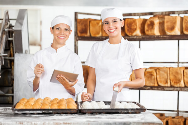 Smiling Female Colleagues With Digital Tablet In Bakery
