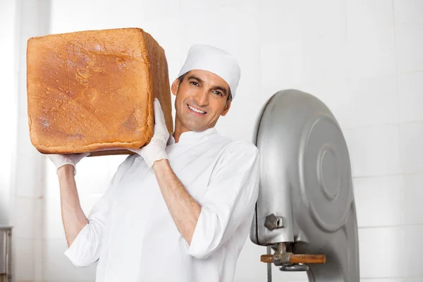 Confiado panadero llevando pan grande pan en el hombro en panadería — Foto de Stock