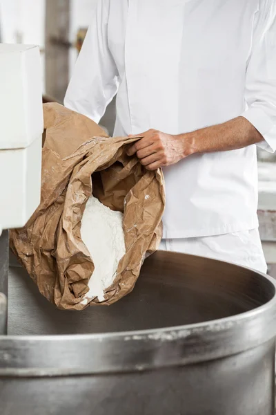 Midsection de maduro Baker derramando farinha na máquina de amassar — Fotografia de Stock