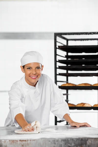 Happy Female Baker Farinha de limpeza da mesa — Fotografia de Stock