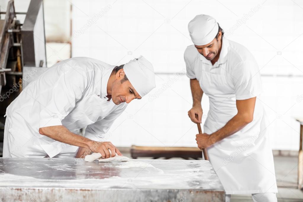 Baker Cleaning Table While Colleague Using Mop — Stock Photo
