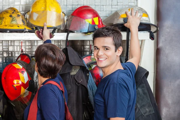 Glücklicher Feuerwehrmann mit Kollege, der Helm abnimmt — Stockfoto