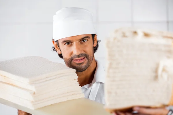 Panadero masculino seguro con rebanadas de pan — Foto de Stock