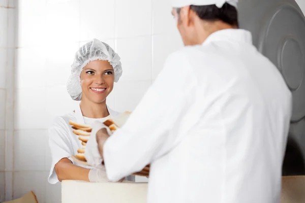 Vrouwelijke Baker brood ontvangstinrichtingen van mannelijke collega — Stockfoto