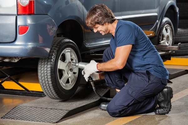 Meccanico di fissaggio auto pneumatico presso officina di riparazione — Foto Stock