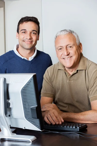 Glad lärare och Senior Man på datorn skrivbord i klassrummet — Stockfoto