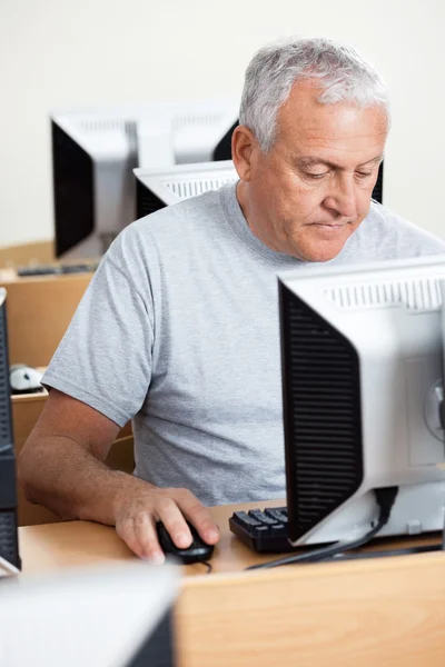 Hombre mayor usando la computadora en el escritorio en el aula —  Fotos de Stock