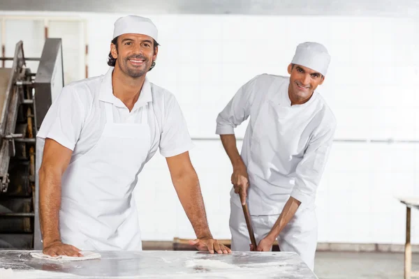 Szczęśliwy piekarzy mężczyzna w mundurze czyszczenia piekarnia — Zdjęcie stockowe