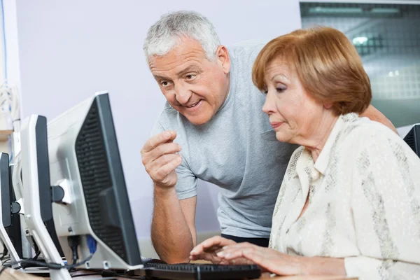Hombre mayor ayudando a la mujer en la clase de informática — Foto de Stock