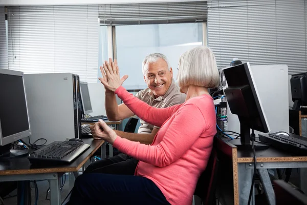 Старшие люди, дающие пять в компьютерном классе — стоковое фото