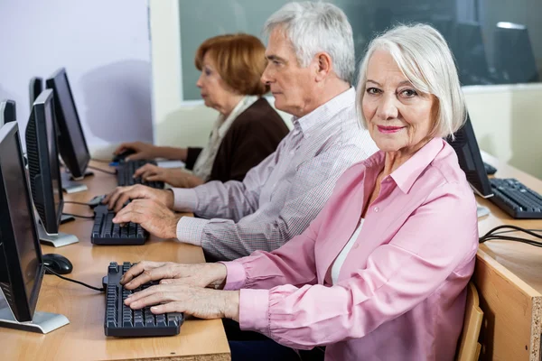 Sorrindo mulher sênior na mesa na aula de informática — Fotografia de Stock