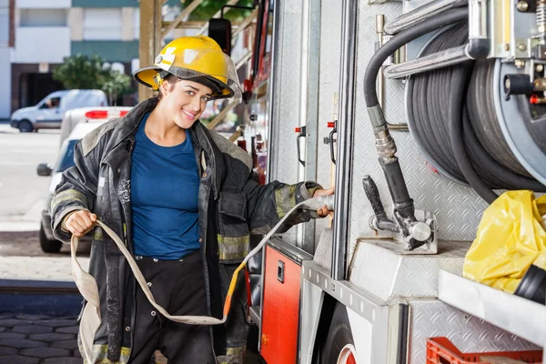 Pompiere sorridente Regolazione del tubo dell'acqua nel camion — Foto Stock