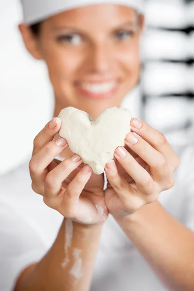 Baker κρατώντας καρδιά σχήμα ζύμη σε αρτοποιείο — Φωτογραφία Αρχείου
