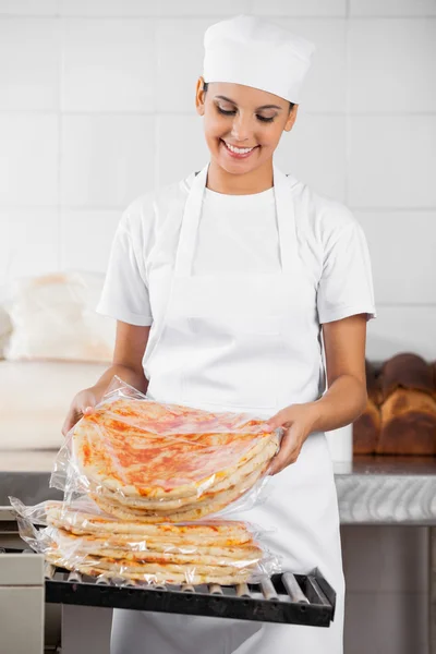 Vrouwelijke Baker stapelen verpakt Pizza brood — Stockfoto