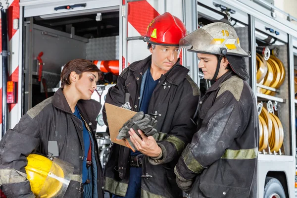 Feuerwehrmann zeigt Kollegen Klemmbrett — Stockfoto