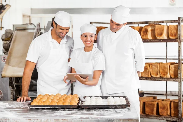 Улыбающаяся женщина с помощью цифровых технологий с коллегами в пекарне — стоковое фото