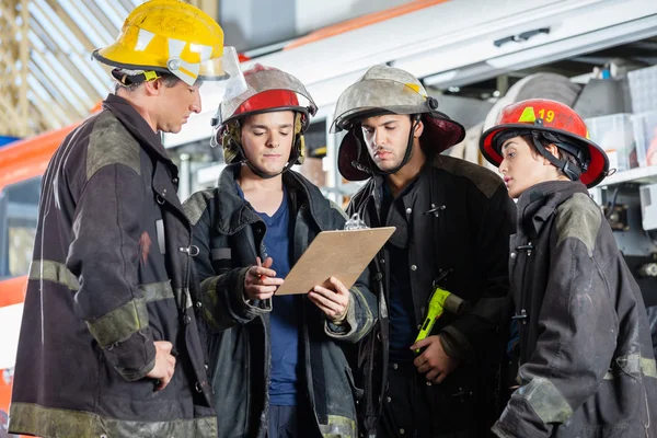 Bombeiros lendo área de transferência no quartel de bombeiros — Fotografia de Stock