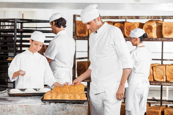 Baker analyse les pains tout en collègues travaillant dans la boulangerie — Photo