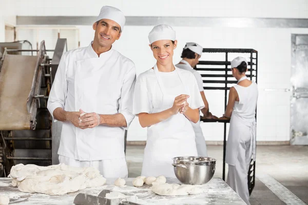 Panaderos sonrientes haciendo bolas de masa en panadería — Foto de Stock