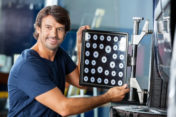 Felice meccanico utilizzando ruota allineatore su auto — Foto Stock