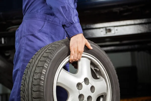 Mechanic Carrying Tire At Garage — Stock Photo, Image