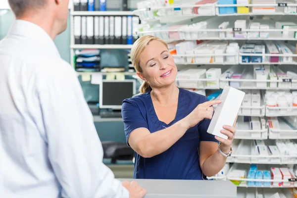 Farmacéutico mostrando detalles del producto al cliente en farmacia — Foto de Stock