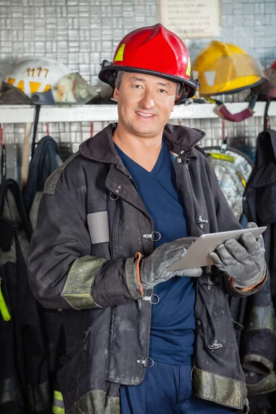 Улыбающийся пожарный держит планшет на пожарной станции — стоковое фото