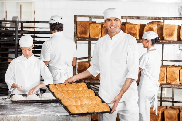 Confiado macho panadero mostrando pan en panadería —  Fotos de Stock