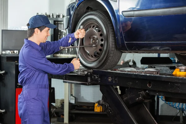 Meccanico di fissaggio auto pneumatico presso officina di riparazione — Foto Stock