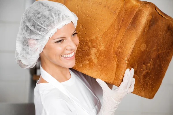 Zbliżenie Baker uśmiechający się podczas przewozu chleba duży bochenek — Zdjęcie stockowe