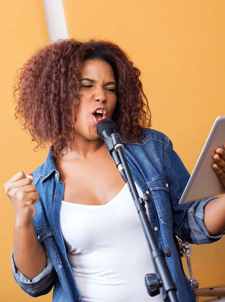 Gepassioneerde zanger tabletcomputer te houden tijdens het uitvoeren van — Stockfoto