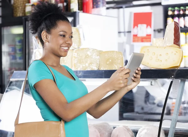 Frau hält digitales Tablet im Supermarkt — Stockfoto