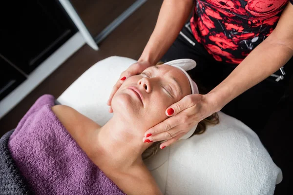Косметолог дає масаж обличчя клієнту в салоні — стокове фото