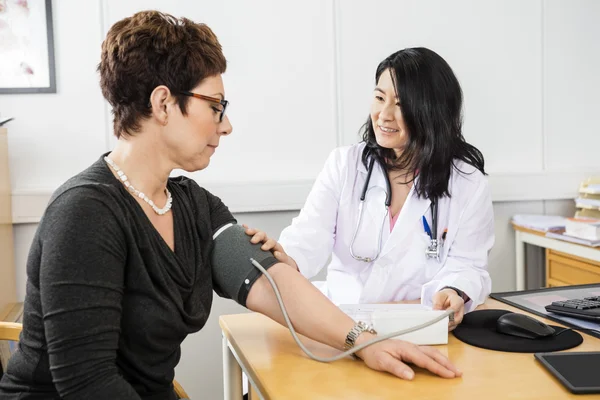 Dokter onderzocht vrouwelijke patiënten bloeddruk — Stockfoto