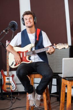 Kendine güvenen adam taburede oturan süre gitar çalmak