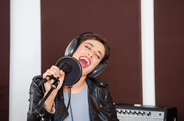 Mujer con los ojos cerrados cantando en el estudio —  Fotos de Stock