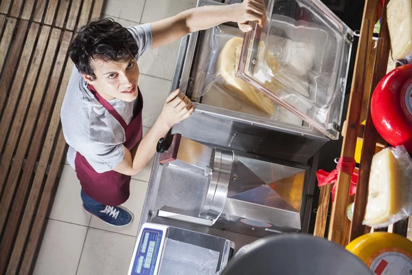 Vendedor embalaje de queso en la máquina de vacío en la tienda de comestibles — Foto de Stock