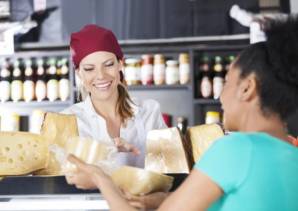 Ekspedientka wspieranie młodych klientów w kupowaniu serów — Zdjęcie stockowe