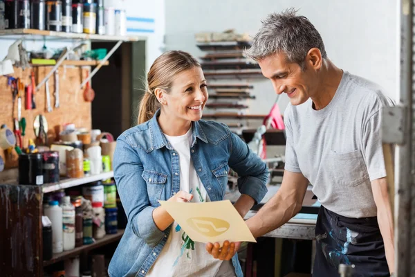 Werknemer bedrijf papier terwijl collega glimlachend op hem — Stockfoto