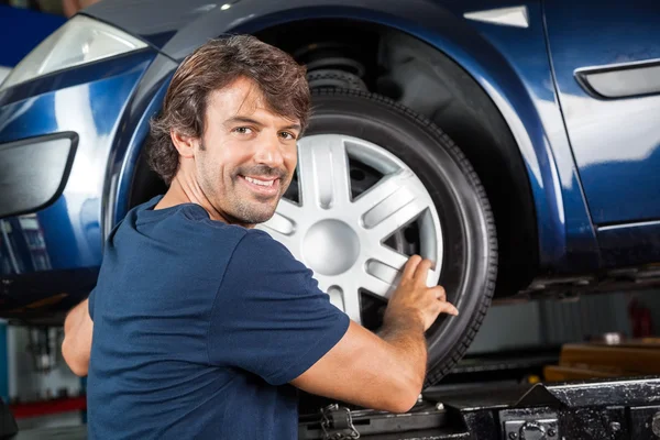 Confident Mechanic Fixing Alloy To Tire Stock Picture