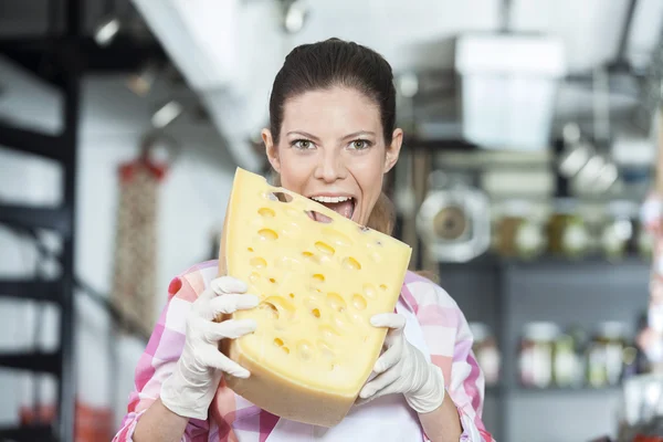 Jovem vendedora mordendo queijo na loja — Fotografia de Stock