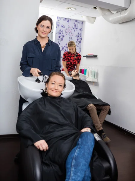 Friseur wäscht Damenhaare im Salon — Stockfoto