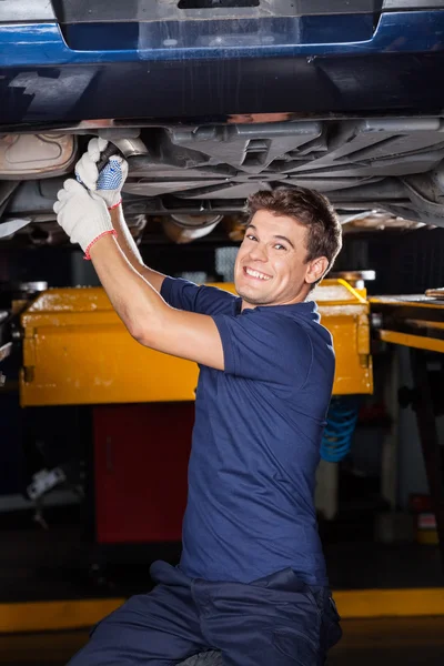 Trabajo mecánico feliz debajo del coche levantado — Foto de Stock