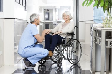 Wheelchai üst düzey Womans yandan gülümseyen tutan fizyoterapist