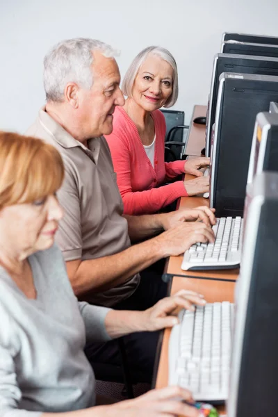 Mulher Sênior feliz usando o computador na classe — Fotografia de Stock