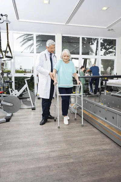 Fisioterapeuta asistiendo a la mujer con Walker en el centro de rehabilitación —  Fotos de Stock