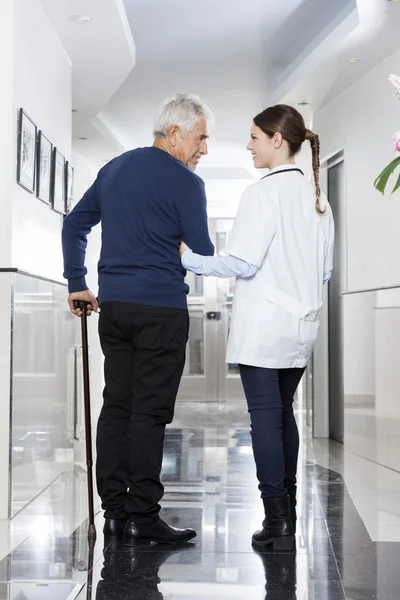 Médico femenino que ayuda al hombre a caminar en el centro de rehabilitación — Foto de Stock