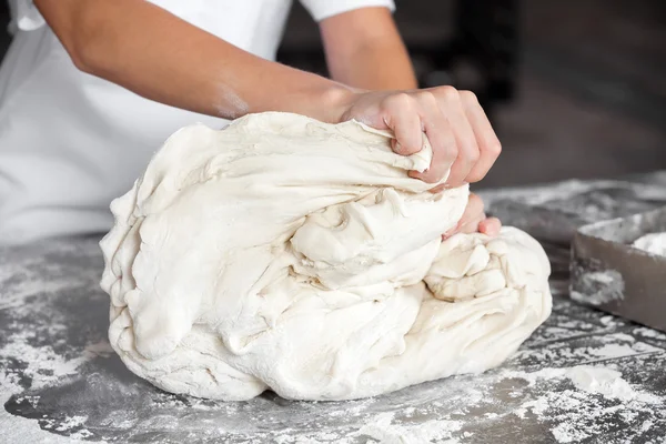 Panaderos manos amasar la masa en la mesa — Foto de Stock