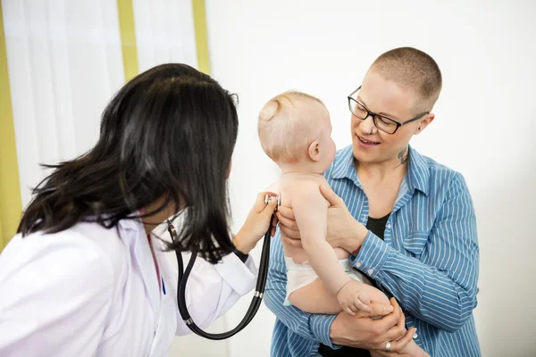 Femmina pediatra esaminando bambino portato da madre — Foto Stock